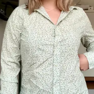 Vit skjorta från BLÄCK, tailored fit, storlek L med små, gröna blommor på. Unisex. Knappt använd på grund av fel storlek, men jättefin! Passar bra till både vardag och fest skulle jag säga :)