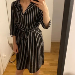 En randig skjortklänning  - En klänning som kommer lite över knäna. Storlek 34/36, den är stor i storleken