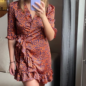 Omlottklänning  - Omlottklänning orange/marinblå från Boohoo. Använd en gång, bra skick. Strl 36. Kan mötas upp i Linköping annars tillkommer frakt 