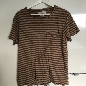 Brunrandig T-shirt - En löst sittande T-shirt i storlek L. Frakt: 44 kr ej spårbart (63 kronor med spårbart postnord). SAMFRAKTAR