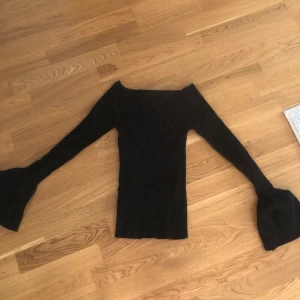 Svart ribbad tröja. - Svart ribbad tröja från Gina tricot. Armarna är utsvängda. 