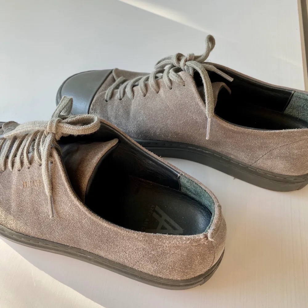 Hej! Jag säljer ett par axel arigato skor i färgen grå. Riktigt snygga och i bra skick. Finns en liten skråma på ena skon (se bild) annars jättefina och fräscha. . Skor.