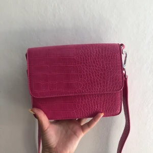 Rosa Handväska - Oanvänd rosa handväska från Gina Tricot. En perfekt färgklick till outfiten!! Säljes på grund av att den inte kommer till användning. Nypris 299kr. Pris kan diskuteras så båda blir nöjda! Köpare står för frakt, men kan även mötas upp. 