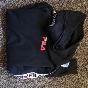 Hoodie Fila - Svart hoodie med detaljer på armarna, från Fila. Storleken är stor med stor luva. Storleken s och jag är 169cm.