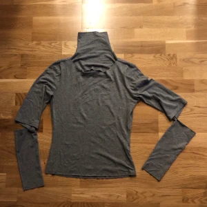 Grå turtleneck med öppna armar och öppen byst - Fin, stretchig tröja med turtleneck och öppna armar och byst. Sitter fint. Passar mig som är M. 