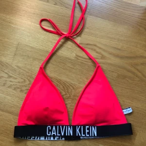 Oanvänd bikinitopp Calvin Klein  - Jättesöt bikiniöverdel från Calvin Klein. Stark röd/rosa färg. Stolek M men skulle säga att den även passar S. Helt oanvänd. Säljer pga. har två likadana. Köparen står för frakt!🌸