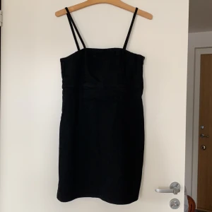 Miniklänning i svart jeansmaterial - Använd ett fåtal gånger, sitter väldigt snyggt. Spagettiklänning. Mjukt jeanstyg. 90-tal. 