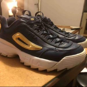  -  Fila x Urban Outfitters Världens finaste Disruptors i marinblått och guld. Köpta i februari men används inte alls. Varsamt använda de gånger de an ants. Har ett litet litet slitage i ena hälen då jag är för lat för att knyta upp skorna. 