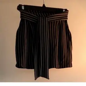 Green, black and khaki striped mini skirt with front tie and pockets. Stretch material in the back. From Pull & Bear