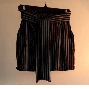 Striped mini skirt size S - Green, black and khaki striped mini skirt with front tie and pockets. Stretch material in the back. From Pull & Bear