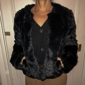 Pälsjacka  - Jacka i pälsimitation utan krage och har knappar att stänga jackan med. 