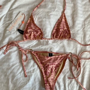 Fin bikini till sommaren/aldrig använd! - En fin rosa bikini med mönster🌸! Bikinin är aldrig använd och är i storlek S (både över och underdelen). Är köpt i en NAKD OUTLET märket är SWIM MINKPINK. Köparen står för frakten.💕🌷
