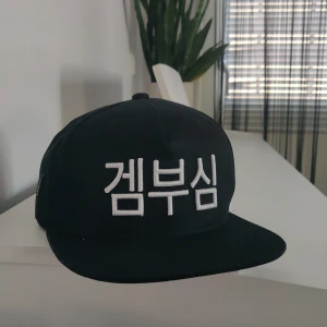 Snapback från DRKN - Svart snapback med vit text från märket DRKN. Justerbar i storlek - passar alla. Nyskick!