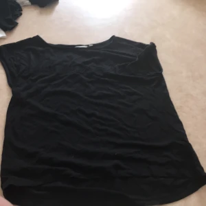 T shirt - en fin svart t shirt använd några gånger förra året. Det är några fina detaljer i svart på ärmarna och lite över brösten. frakt inkluderat.