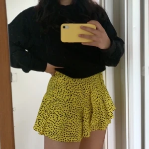 Gul somrig miniskirt med svarta prickar - Köpt i London på Topshop sommaren 2018, använd en gång och i väldigt bra skick! Säljer för att den är lite för liten för mig, men passar XS-M med tanke på banden som går att knytas till önskad storlek! 