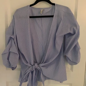 Blå och vit randig blus/topp - Söt blus med puff ärm och knytning ifrån Nelly. Använd få gånger därav i väldigt fint skick!💜