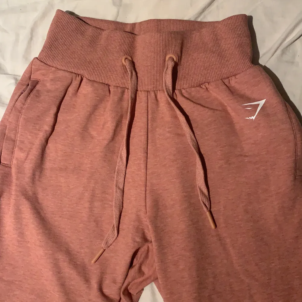 Säljer ett par gymshark mjukis/tränings byxor i storleken S! Färgen är i en typ av stentvättad rosa. Vid benen är de band som man lindrar runt benet för att få en fin detalj. Använt dem 1 gång men säljer dem då de aldrig kommer till användning😊. Jeans & Byxor.