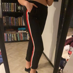 Svarta byxor - Svarta byxor med vit och röd rand på sidan. Ganska korta på mig som är 172. Köpta på Zara. Står att de är i storlek 5 vilket jag gissar på är S. Frakt tillkommer.