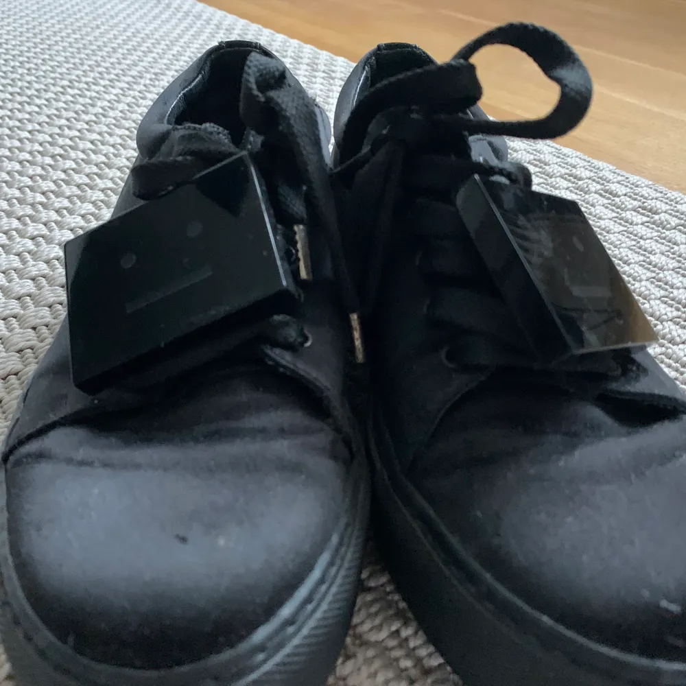 Svarta sneakers från Acne Studios i silkigt material och med den klassiska loggan!  Så snygga skor men har för många svarta så hoppas någon annan får mer användning av dem.  De är använda men fortfarande sjukt fina, fråga för mer bilder 🥰. Skor.