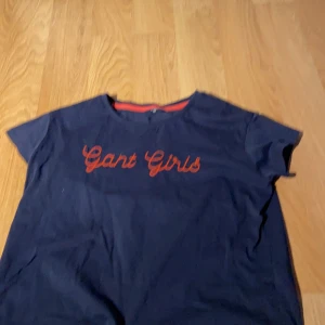 Gant t-shirt från Kidsbrandstore i st.146-152 - Marinblå gant t-shirt där de står ”gant girls”. Andvänd ca.3ggr p.g.a att den blev förliten. I väldigt fin skick!