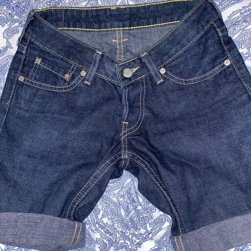 Ett par längre shorts från Levis i en fantastisk mörkblå färg. Storlek 25x31. Stängs med knappar. Hittar inga slitningar. Säljes pågrund av att de är för små.. Shorts.