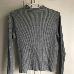  - Ribbad grå långärmad tröja med en liten polokrage.   Köparen står för frakt ;)