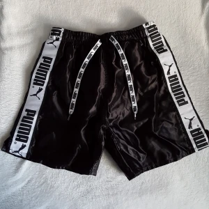  - Vintage svarta glansiga Puma shorts, storlek 160 men passar ca strl XS/S med. Har ett pyttelitet hål i innerfodret som kan ses på sista bilden. Kan skickas om köparen står för frakten.
