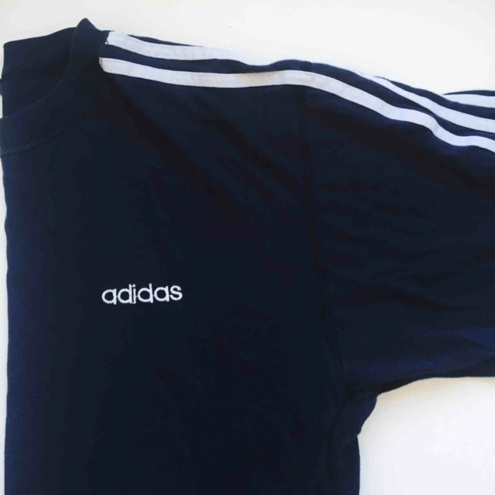 Oversized Adidas t-shirt, mörkblå med vita detaljer, köpt vintage. Bra skick, avklippta nedtill av förra ägaren. Passar som XS-M. Säljer för 50kr + eventuell frakt. . Skjortor.