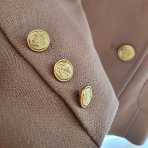  - Kanske den mest klassiska och snyggaste höstkappan du kan tänka dig. Den perfekta beiga färgen tillsammans med guldiga detaljer och rött innertyg. Lyx i dess billigaste form.  Inköpt på H&M  Sparsamtanvänd   Kan nötas upp i Huddinge, Älvsjö, Årsta, Globen & Västberga