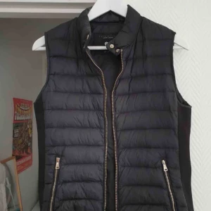  - Stilren dunväst från Zara. Väldigt liten i storleken, L passar S/M. Mycket bra skick. Frakt ingår!