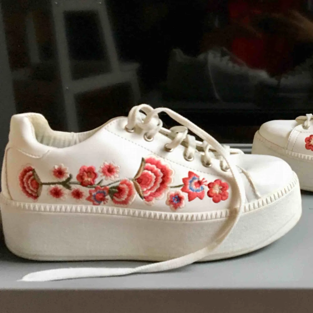 Ett par vita sneakers med blommor! Använda men inte så slitna och bra skick🌺🌺. Skor.