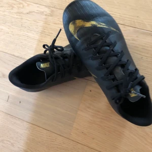 Nike mercurial fotbollsskor  - Svarta och guldiga fotboll storlek 37,5. Köptes i våras knappt använda. Sälj för de är för små.
