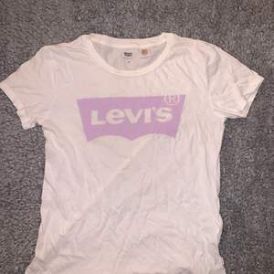 En vit Levis T-shirt med ett rosa/lila Levis märke💕 den sitter hyfsat tajt på och är i mycket bra skick, det är bara å skriva om det är några frågor☺️