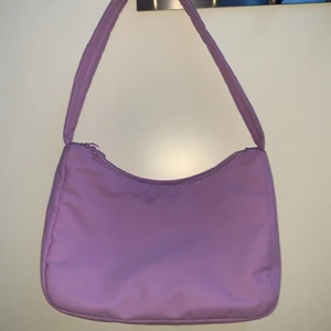 Väska från Gina Tricot  - Det är en lila väska, den är liten och den är i nyskick. Original pris är 250kr.