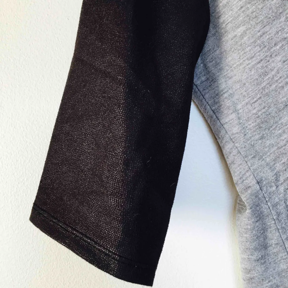 Ljusgrå tröja med runt material och svarta skinnliknande (fakeskinn) detaljer kring hals och ärmar. Gott skick använd ett fåtal gånger! Frakt 20kr. Toppar.