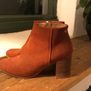 Oranga boots med träklack - Oranga boots i mockaimitation med guldiga detaljer och träklack. Från märket novita, originalpris ca 1000kr. Klacken är ca 5-6cm 