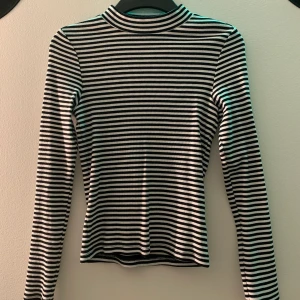 Randig tröja med kort polikrage - En randig tröja med en kort polokrage. Bra skick och stretchigt material vilket ger en tajt fit i storleken xs men skulle nog passa en s. 