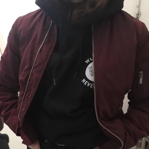 Vinröd bomberjacka.  - Jackan är i fint skick. Väldigt lite använd. Köpt från JC, nypris ca 700:- Storkek XXS men är som en S skulle jag säga. Säljer på gund av att den bara hänger i garderoben :) Köparen står för frakt kostnad!