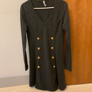 Klänning grå - Grå klänning med guldknappar framtill och på armarna 