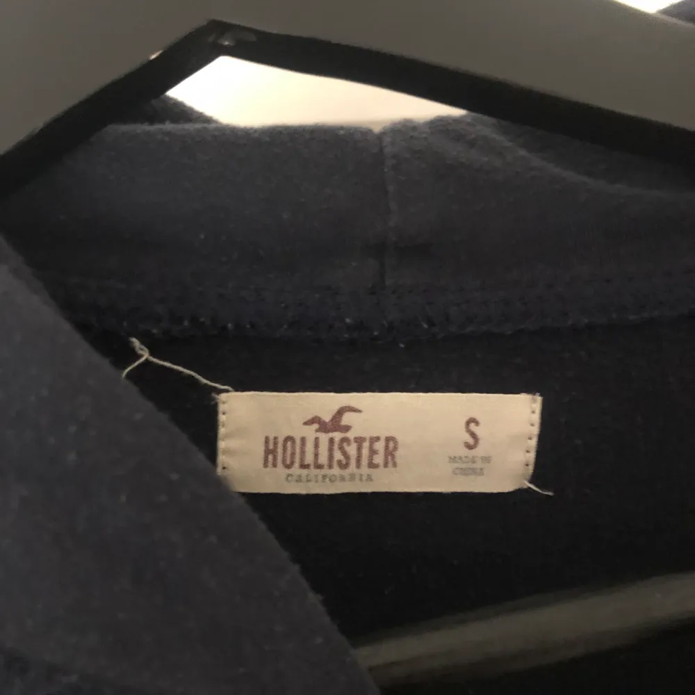 En marinblå Hollister hoodie med rosa detaljer. I storlek s men passar även dem som är xs. Köptes i en Hollister butik för 400kr. Använd några gånger men i ett väldigt bra skick. Säljer pågrund av att jag har för många hoodies. Köparen står för frakten💕. Hoodies.
