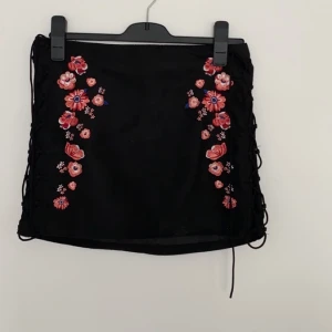 Svart kjol  - Svart kjol från h&m med blommiga detaljer. Kan sänka priset vid köp av flera plagg 