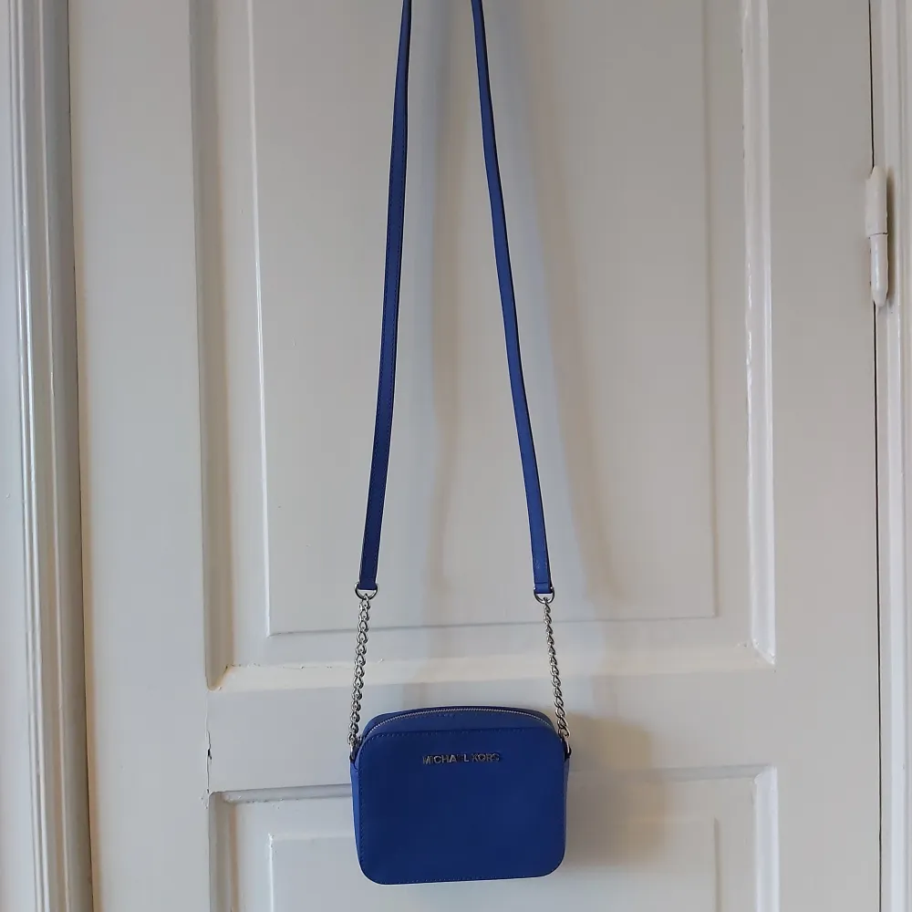 Fin liten blå crossbodyväska med silvriga detaljer från Michael Kors. Självklart äkta, köpt på NK för ca 5 år sedan. Kommer aldrig till användning då den inte är min stil, använd max 3 gånger. Kan mäta hur stor den är om nån önskar.. Väskor.