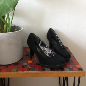 Marco tozzi klackar 👠  - Ett par jättefina klackar ifrån marco tozzi! Svart mocka på utsidan och glansigt tyg på insidan. Varsamt använda och ytterst lite sliten på kanten av sulan. Men annars inga skador. Frakt tillkommer👠