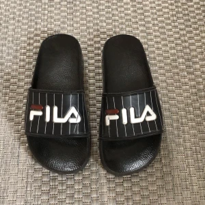 FILA tofflor - Snygga fila tofflor/badtofflor i bra skick. Lite slitningar på filamärket samt ”sprickor” över filamärket om jag uttrycker mig rätt:) 