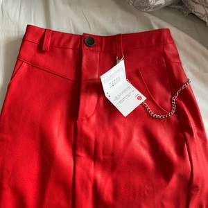 ”Skinn” kjol med kedja  - Helt oanvänd röd kjol med kedja som tillkommer. Skulle ha den förra halloween men den passade inte så alla prislappar sitter även kvar. 