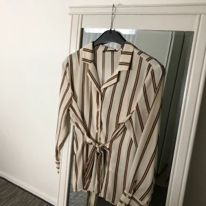 Skjorta/blus  - En crémefärgad skjorta med bruna ränder. Storlek 38 (M), ganska ny och använt bara en gång. Frakt förekommer. För fler frågor och bilder skriv till mig!   