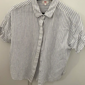 LEVI’s kortärmad randig skjorta - Vit skjorta med ljusblå ränder. I strl M, skulle säga passar en 36/38a i storlek. 55% linnen och 45% viskos.  200kr inkl frakt eller möts upp i Borlänge 💕