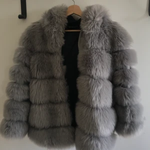 Pälsjacka  - Grå fake pälsjacka med luva. Köpt från Veraldo.dk. Använd ett antal gånger. 500kr + frakt. 