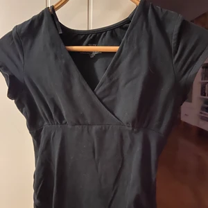 Svart tshirt med detaljer vid brösten - Den här svarta t-shirten är väldigt fin, och har många intressanta detaljer! Den är tyvärr för liten för mig, men kan nog bli riktig snygg på en ny ägare! Inte så använd!