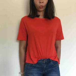  - En röd t-shirt med detaljer på sidorna med band och metall. Kostar 150kr inklusive frakt.